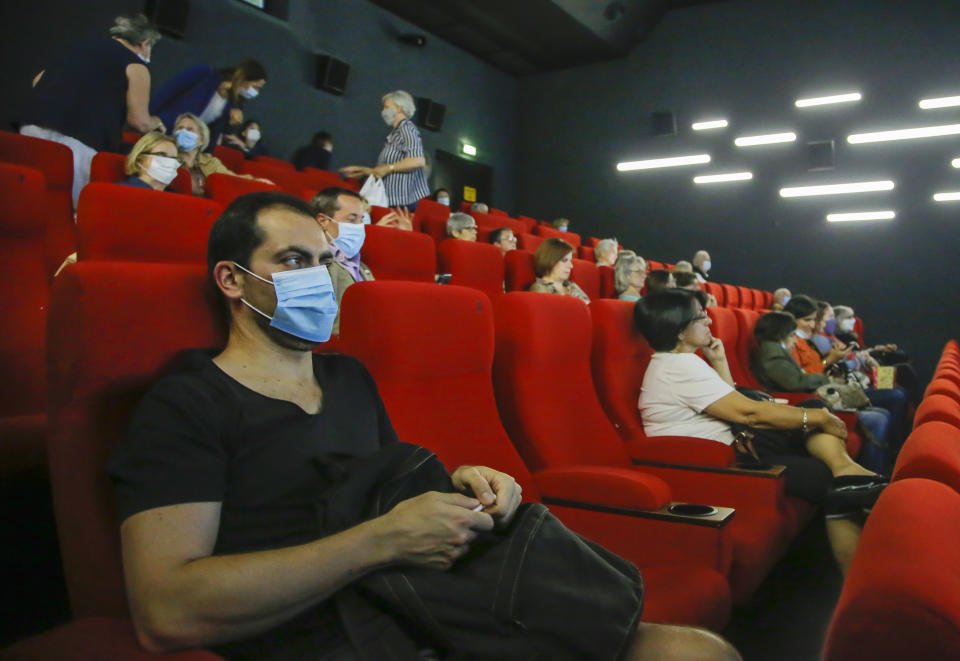 People wear protective masks as they wait for the screening of a movie in Paris, Monday, June 22, 2020. Movie theaters are reopening across the country after three months of closure due to the COVID-19 lockdown measures. (AP Photo/Michel Euler)
