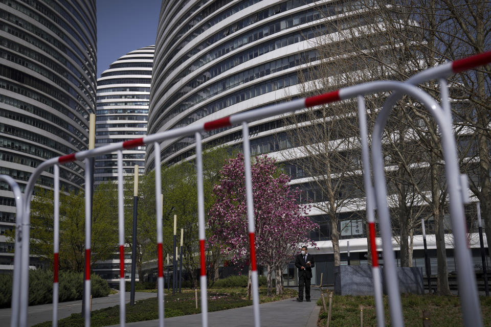 A security guard wearing a face mask stands watch over a barricaded Galaxy Soho commercial office building locked down for health monitoring following a COVID-19 case detected in the area, Tuesday, April 5, 2022, in Beijing. China has sent more than 10,000 health workers from across the country to Shanghai, including 2,000 military medical staff, as it struggles to stamp out a rapidly spreading COVID-19 outbreak in China's largest city. (AP Photo/Andy Wong)