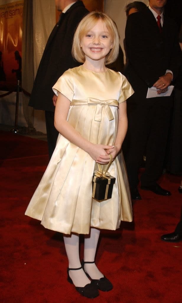 a cap-sleeved dress with a pleated skirt and an empire waist with a bow, paired with a tiny purse shaped like a giftbox