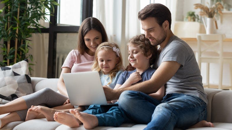 Married couple and kids using laptop