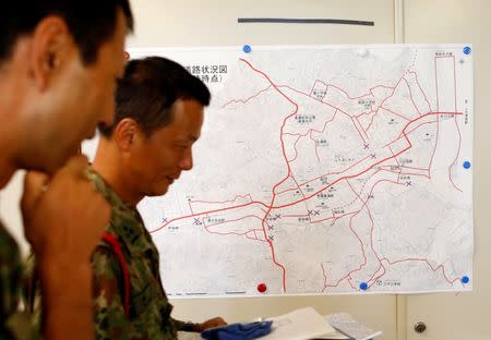 Japan Self-Defence Force soldiers walk past in front of a disaster map at disaster countermeasures headquarters at Kurashiki city government office in Kurashiki, Okayama Prefecture, Japan, July 14, 2018. REUTERS/Issei Kato