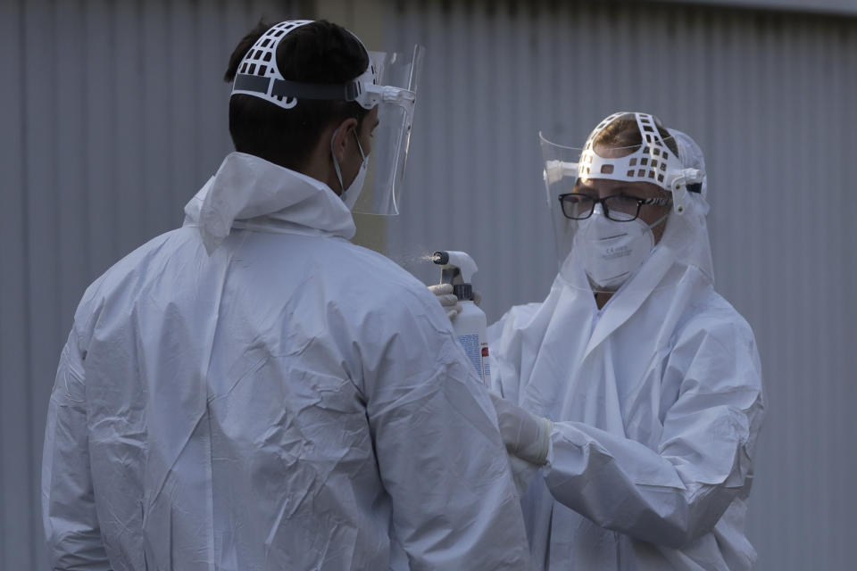 A healthcare worker has his protective suit disinfected at a sampling station for COVID-19 in Prague, Czech Republic, Monday, Sept. 21, 2020. The country coped well with the first wave of the coronavirus infections in the spring but has been facing a record surge of the new confirmed cases last week. (AP Photo/Petr David Josek)