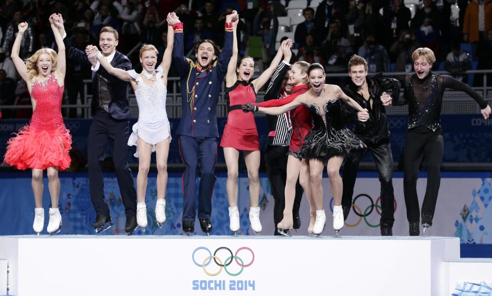 The Russian team jump onto the podium during the flower ceremony after placing first in the team figure skating competition at the Iceberg Skating Palace during the 2014 Winter Olympics, Sunday, Feb. 9, 2014, in Sochi, Russia. (AP Photo/Bernat Armangue)