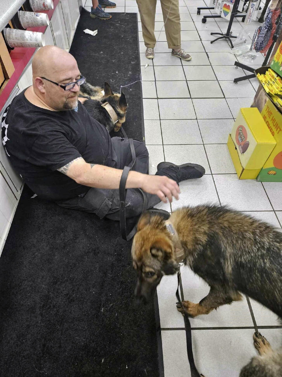 In this photo provided by the Humane Society of Hobart, Ind., a dog suffering from heat-related injury is aided by a man inside the Road Ranger convenience store, in Lake Station, Ind., July 27, 2023. (Jennifer Webber/Humane Society of Hobart, Ind. via AP)
