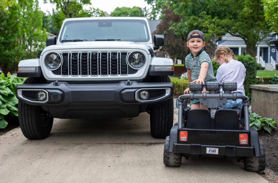 Bertie Doherty, 5, stands on his Power Wheels Jeep Wrangler with his sister Minnie, 3, as they are parked next to a real Jeep Wrangler early in the morning in Birmingham on Wednesday, June 26, 2024.