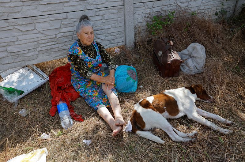 Una mujer se sienta en el suelo con un perro tras ser evacuada de una zona inundada tras el colapso de la presa de Nova Kajovka en el transcurso del conflicto entre Rusia y Ucrania, en la localidad de Hola Prystan, en la región controlada por Rusia de Jersón, Ucrania