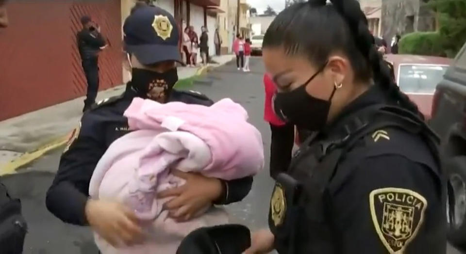 A policewoman can be seen holding the baby after it was wrapped in blankets. Source: RealPress/Australscope