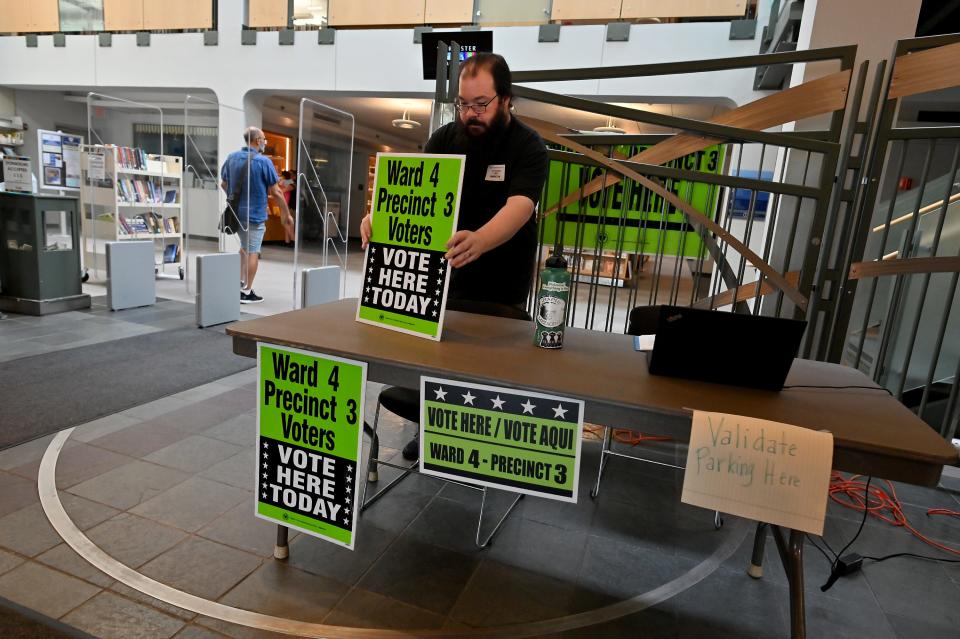 Elections inspector Matthew Noe puts out another sign as voting continues at the Worcester Public Library on Tuesday morning.