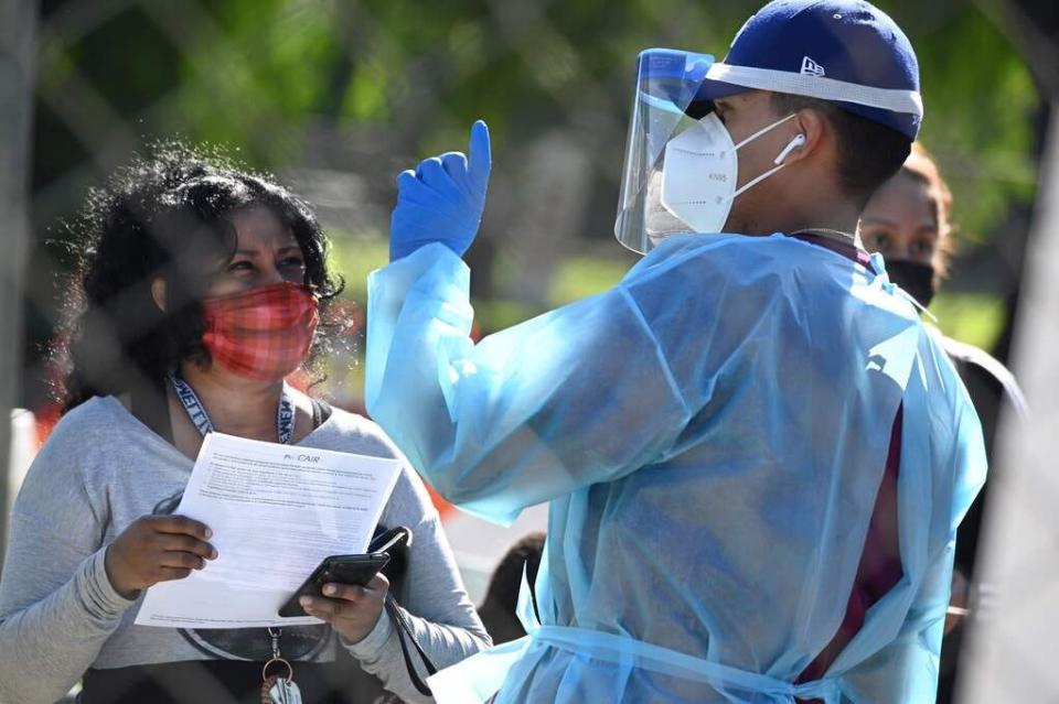 A healthcare worker speaks to a woman at a walk-up Covid-19 testing site, November 24, 2020, in San Fernando, California, just northeast of the city of Los Angeles.  California shattered the state's single-day COVID-19 record with over 20,500 new cases recorded on November 23 ahead of the Thanksgiving holiday.