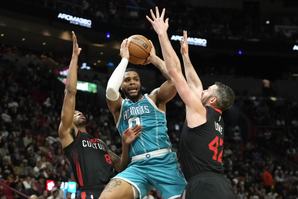 Charlotte Hornets forward Miles Bridges (0) looks to pass as Miami Heat forwards Jamal Cain (8) and Kevin Love (42) defend during the second half of an NBA basketball game, Wednesday, Dec. 13, 2023, in Miami. (AP Photo/Lynne Sladky)