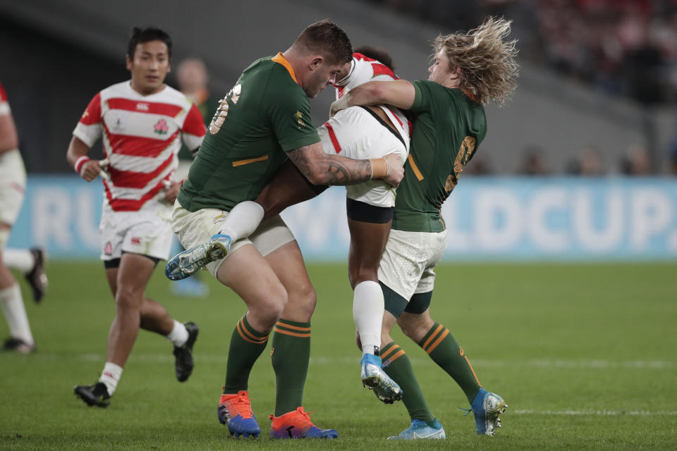 South Africa's Malcolm Marx and South Africa's Faf de Klerk (9) picks up Japan's Kotaro Matsushima during the Rugby World Cup quarterfinal match at Tokyo Stadium between Japan and South Africa in Tokyo, Japan, Sunday, Oct. 20, 2019. (AP Photo/Jae C. Hong)
