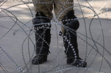 An Indian police officer stands behind the concertina wire during restrictions on Eid-al-Adha after the scrapping of the special constitutional status for Kashmir by the Indian government, in Srinagar