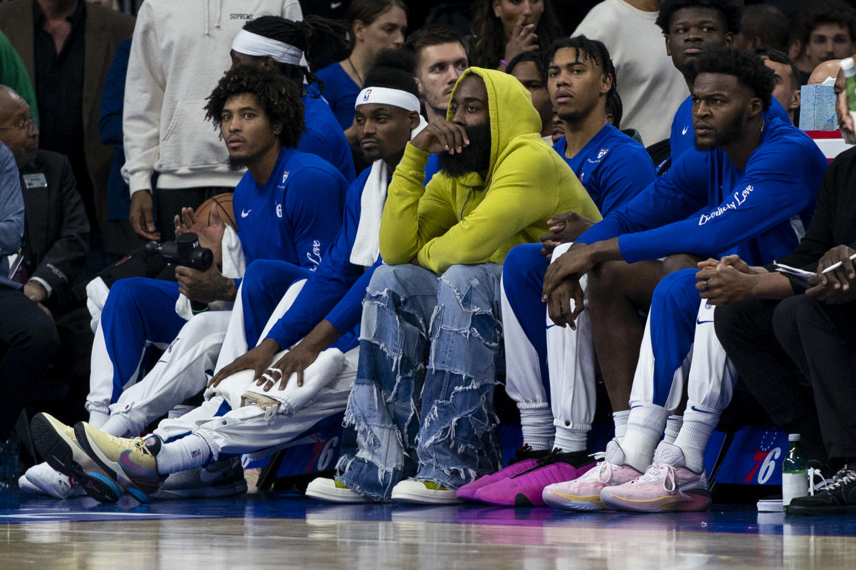 Philadelphia 76ers' James Harden, center, looks on from the bench in street clothes during the NBA basketball game against the Portland Trail Blazers, Sunday, Oct. 29, 2023, in Philadelphia. The 76ers won 126-98. (AP Photo/Chris Szagola)