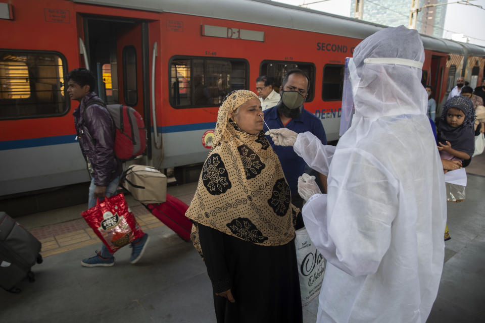 A health worker takes a swab sample of a traveler to test for COVID-19 at a train station in Mumbai, India, Thursday, Dec 30, 2021.(AP Photo/Rafiq Maqbool)