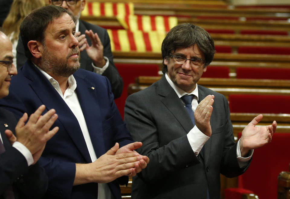 Carles Puigdemont, derecha, presidente regional de Cataluña, aplaude junto al vicepresidente Oriol Junqueras, izquierda. (AP Foto/Manu Fernández)