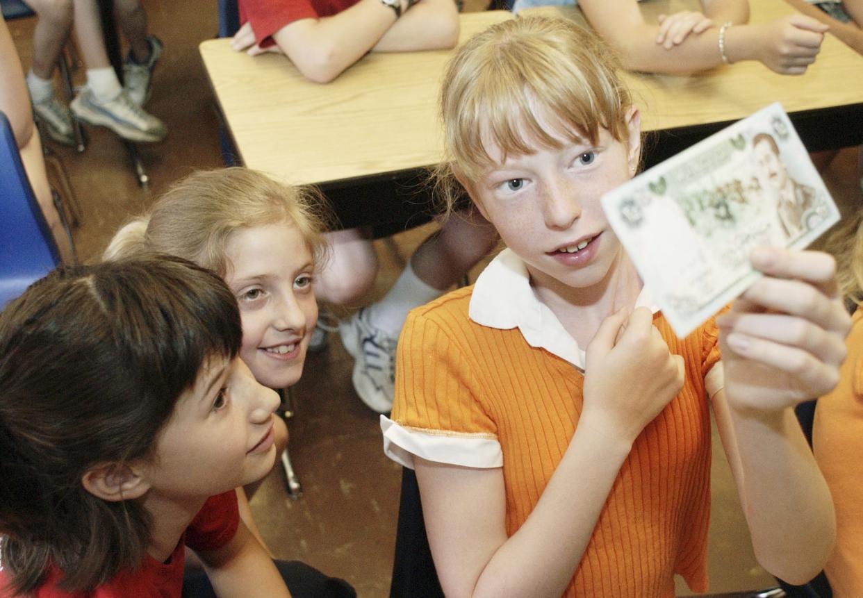 Fifth-graders Caitlyn Black, left, Elizabeth Wiessinger, and Alexandra Rice, all 11, examine a piece of Iraqi currency once worth 25 Dinars. Army Sgt. Bryan Davis, 40, of Baltimore, Ohio, shared it with to 4th and 5th-graders, at Bloom Elementary School, in Lithopolis, Ohio, on Tuesday, May 25, 2004. He recently returned from Kuwait where was serving with the 186th Engineers detachment of the 16th Brigade under the 3rd Army. During his 16 months overseas, he received dozens of personalized letters from the students.
