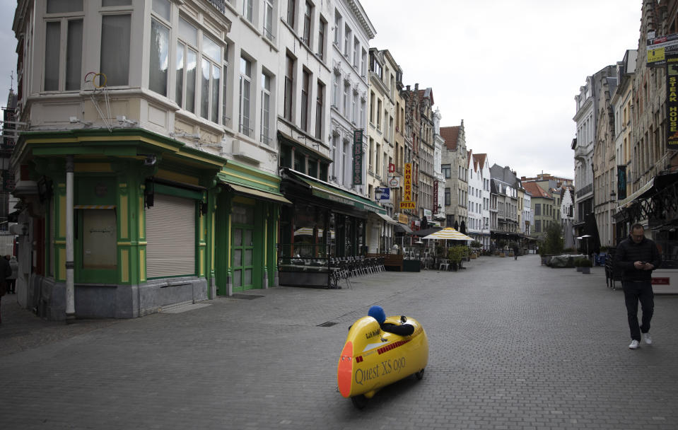 A man rides a pedal car down what would normally be a busy tourist area in the historic center of Antwerp, Belgium, Saturday, March 14, 2020. Belgium has closed schools, restaurants and bars, as as well as cancelled sporting and cultural events in an effort to contain the spread of the coronavirus. For most people, the new coronavirus causes only mild or moderate symptoms, such as fever and cough. For some, especially older adults and people with existing health problems, it can cause more severe illness, including pneumonia. (AP Photo/Virginia Mayo)