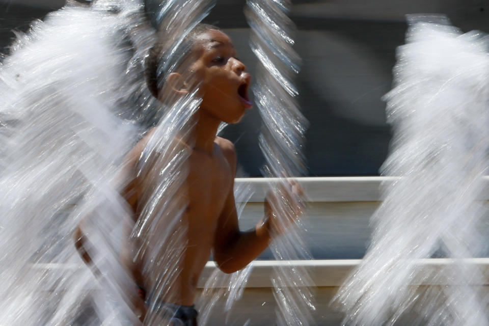 A kid runs splashing water at the Centennial Olympic Park fountains as temperatures rise in Atlanta, Thursday, June 13, 2024. According to the National Weather Service, the temperatures will be in the upper 90s by the weekend. (Miguel Martinez/Atlanta Journal-Constitution via AP)