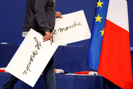 A technician holds placards which reads "I walk" in support of Emmanuel Macron, head of the political movement En Marche ! (Onwards !) and candidate for the 2017 presidential election, before a campaign rally in Pau, Southwestern France, April 12, 2017. REUTERS/Regis Duvignau
