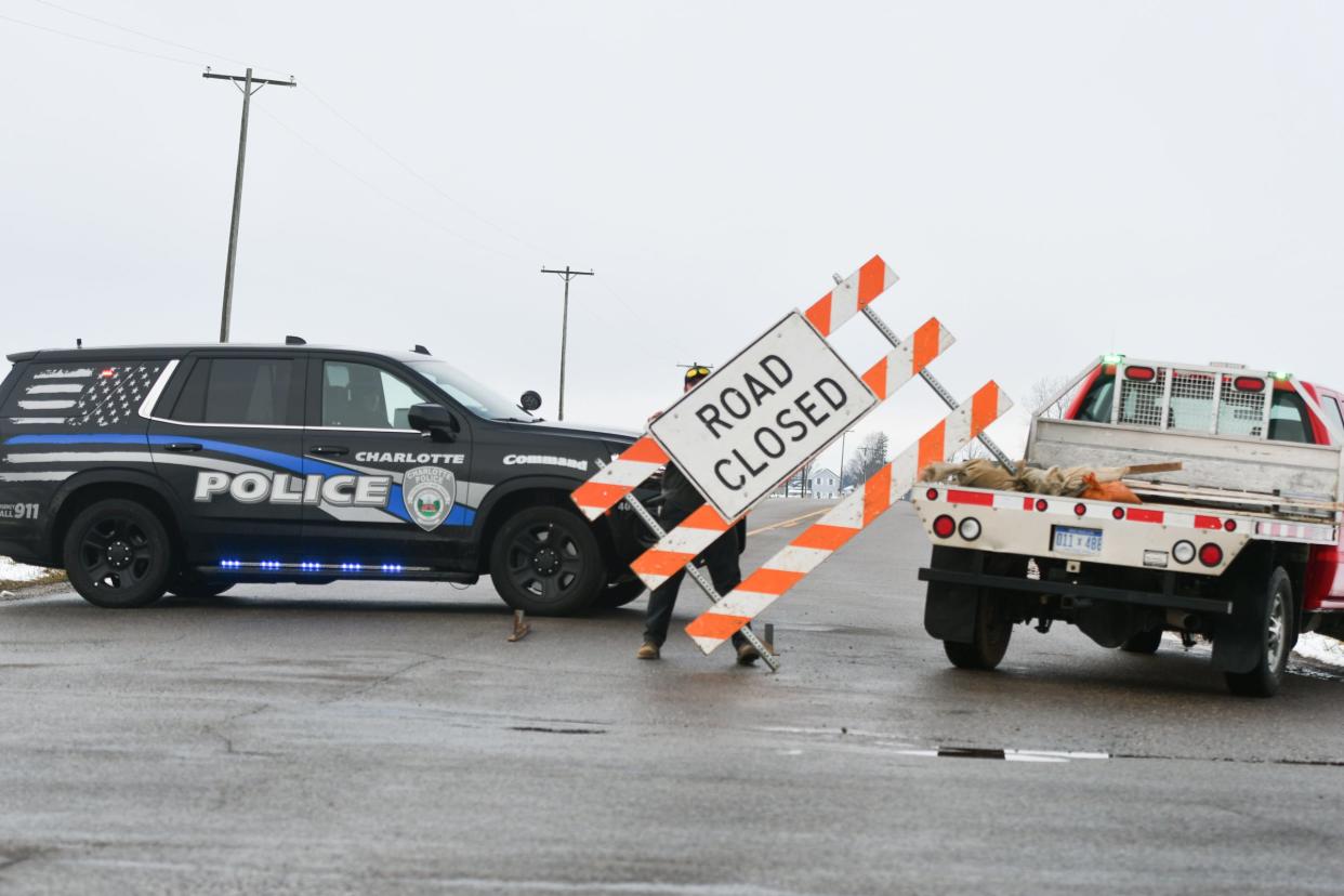 A worker from the Eaton County Road Commission sets up a roadblock at St. Joe Highway and Mulliken Road, Thursday, Jan. 11, 2024, as Charlotte Police block access.