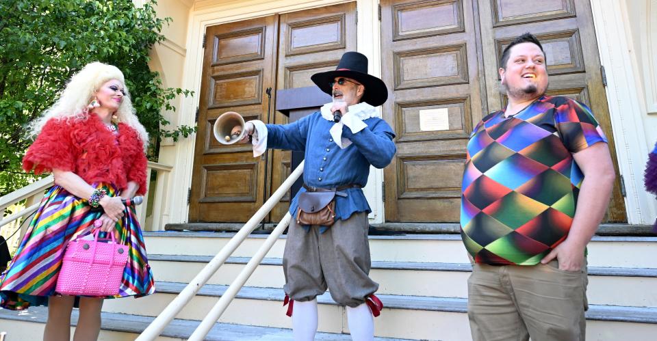 In June 2022, Town Crier Daniel Gómez Llata rings his bell at the Pride rally at Provincetown Town Hall, with Paige Turner (left) and Austin Tyler.