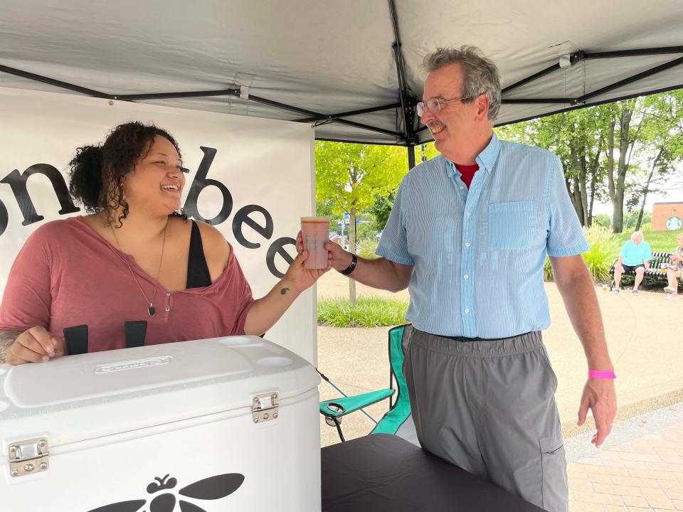 Clissa Patrick with Honeybee serves a specialty cold beer to Joe Carson at the Food Truck Freedom field day at Mayor Ralph McGill Plaza in Farragut Saturday, Aug. 20, 2022.