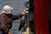 A vendor receives Chinese money after selling North Korean goods to tourists on a boat taking them from the Chinese side of the Yalu River for sightseeing close to the shores of North Korea, near Dandong, China's Liaoning province, April 1, 2017. REUTERS/Damir Sagolj