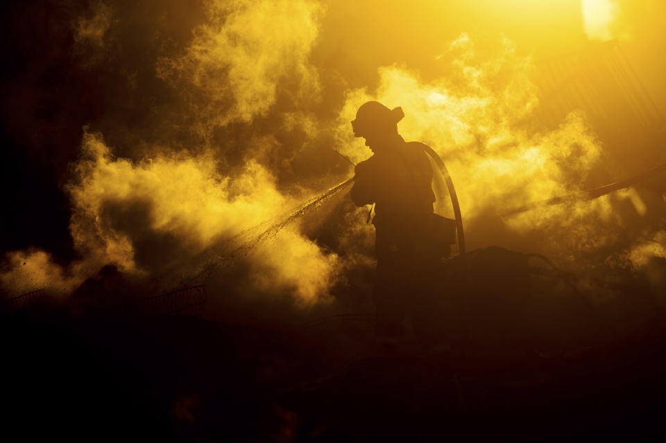 A firefighter sprays water on a leveled home as the Hillside Fire burns in San Bernardino, Calif., on Thursday, Oct. 31, 2019. Whipped by strong wind, the blaze destroyed multiple residences. (AP Photo/Noah Berger)