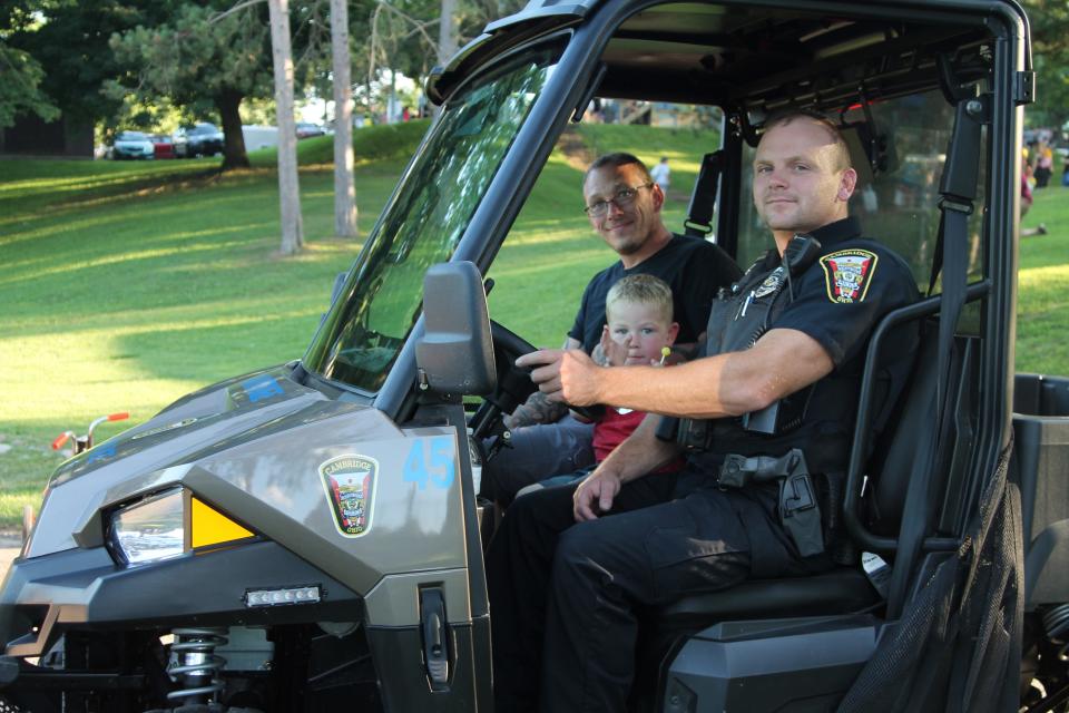 Cambridge Police Officer Adam James give a ride in the side by side to Curtis Patterson and his son Carter, 3, during National Night Out.