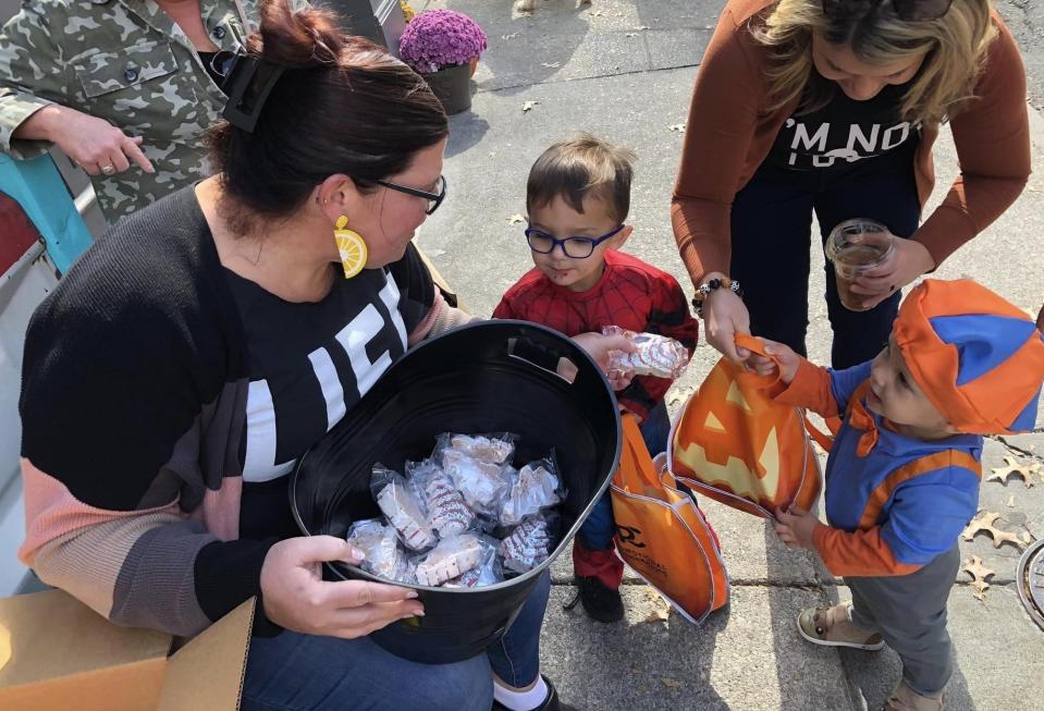 Kat McCay gives Little Debbie Christmas tree cakes to trick-or-treaters Hudson [Spider-Man] and Nash [Blippi] Sandate at Old Towne's Alibi in Petersburg.
