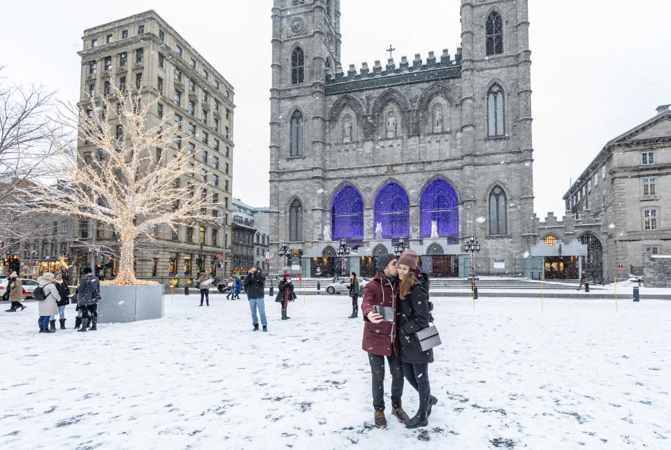 Couple sharing a kiss while they take a selfie outside Notre-Dame Basilica in Montreal during the winter