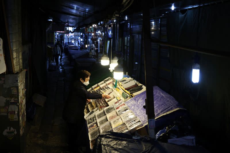 A stall-keeper works among other closed stalls at an empty shopping district amid the COVID-19 pandemic in Seoul