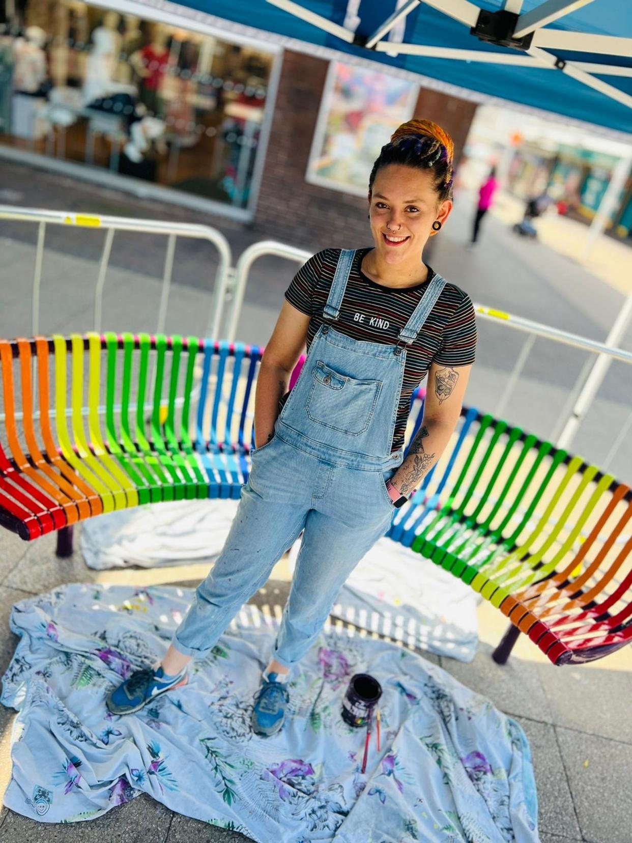 PIC FROM KENNEDY NEWS/ADAM FRAY (PICTURED: FREELANCE ARTIST HANNAH WALTON, 25, WHO PAINTED THE BENCHES STOOD IN FRONT OF ONE) Furious shoppers have branded a shopping centre's rainbow-coloured benches 'woke' - and are even threatening to paint them black. Longton Exchange Shopping Centre in Stoke-on-Trent unveiled two rainbow-coloured 'buddy' benches in May in a bid to combat loneliness. Shoppers are encouraged to take a seat on one of the 'Buddy Benches' to show they either need a chat or are open to having a conversation with someone else. DISCLAIMER: While Kennedy News and Media uses its best endeavours to establish the copyright and authenticity of all pictures supplied, it accepts no liability for any damage, loss or legal action caused by the use of images supplied and the publication of images is solely at your discretion. SEE KENNEDY NEWS COPY - 0161 697 4266