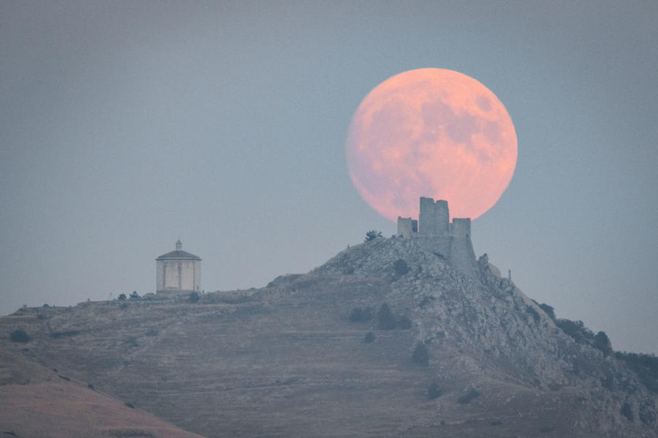 Full harvest moon rising behind a castle and church