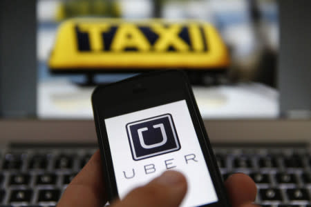 An illustration picture shows the logo of car-sharing service app Uber on a smartphone next to the picture of an official German taxi sign in Frankfurt, September 15, 2014. A Frankfurt high court will hold a hearing on a recent lawsuit brought against Uberpop by Taxi Deutschland on Tuesday. San Francisco-based Uber, which allows users to summon taxi-like services on their smartphones, offers two main services, Uber, its classic low-cost, limousine pick-up service, and Uberpop, a newer ride-sharing service, which connects private drivers to passengers - an established practice in Germany that nonetheless operates in a legal grey area of rules governing commercial transportation. The company has faced regulatory scrutiny and court injunctions from its early days, even as it has expanded rapidly into roughly 150 cities around the world. REUTERS/Kai Pfaffenbach (GERMANY - Tags: BUSINESS EMPLOYMENT CRIME LAW TRANSPORT)