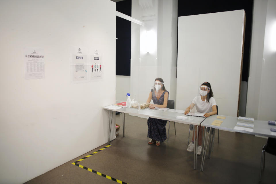 People wearing face mask and visor to protect against coronavirus sit behind a glass shield during a rehearsal of the vote for the local elections scheduled for Sunday, June 28, in Paris, Friday, June 26, 2020. France is to hold its Covid-19 delayed second round of local elections on June 28. (AP Photo/Thibault Camus)