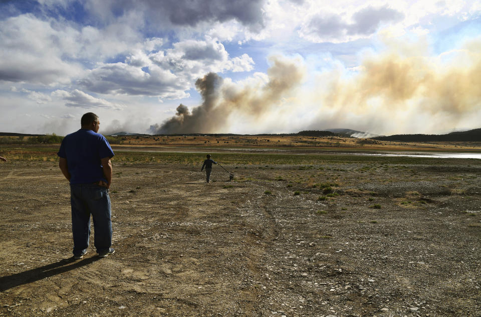 Leonard Padilla and 5-year-old Ivan Padilla watch a wildfire burning near Las Vegas, N.M., on Tuesday, May 3, 2022. Flames raced across more of New Mexico's pine-covered mountainsides Tuesday, charring more than 217 square miles (562 square kilometers) over the last several weeks. (AP Photo/Thomas Peipert)
