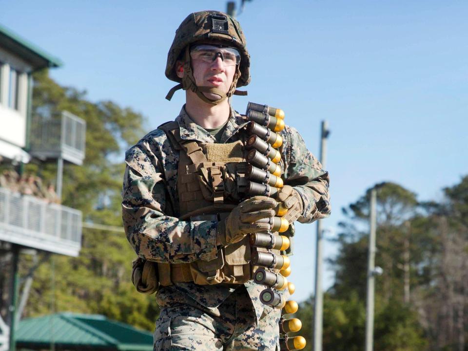 An American soldier with a strip of 40 mm grenade rounds slung over his shoulder.