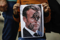 A child holds a photograph of France's President Emmanuel Macron, stamped with a shoe mark, during a protest against France in Istanbul, Sunday, Oct. 25, 2020. Turkish President Recep Tayyip Erdogan on Sunday challenged the United States to impose sanctions against his country while also launching a second attack on French President Emmanuel Macron. Speaking a day after he suggested Macron needed mental health treatment because of his attitude to Islam and Muslims, which prompted France to recall its ambassador to Ankara, Erdogan took aim at foreign critics. (AP Photo/Emrah Gurel)