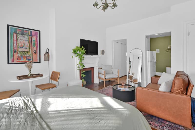 Bedroom area overlooking living room with lounge chair and leather couch.