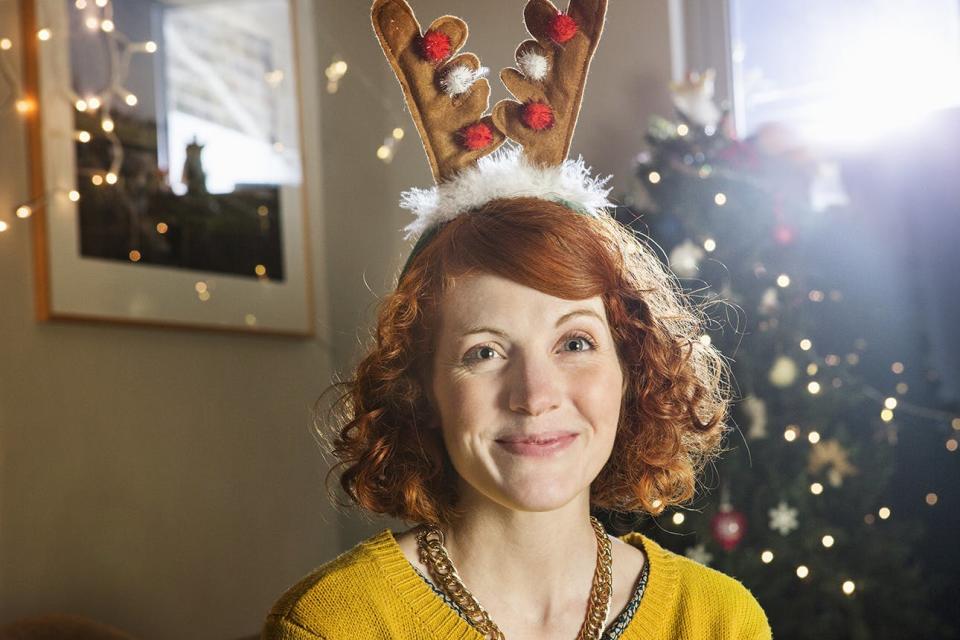 Smiling woman wearing antler headband at Christmas