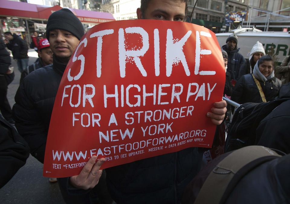 A protester hides his face with a sign outside a McDonald's outlet, as they demand higher wages for fast food workers in the Manhattan borough of New York March 18, 2014. (REUTERS/Carlo Allegri)