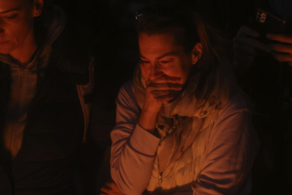 A woman cries as people light candles for the victims near the Vladislav Ribnikar school in Belgrade, Serbia, Wednesday, May 3, 2023. Police say a 13-year-old who opened fire at his school drew sketches of classrooms and made a list of people he intended to target. He killed eight fellow students and a school guard before being arrested. (AP Photo/Armin Durgut)