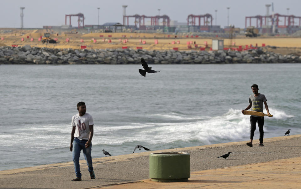 In this Saturday, Nov. 3, 2018, photo, Sri Lankan men walk along the shore near the Chinese funded sea reclamation project in Colombo, Sri Lanka. China and India are closely watching the constitutional crisis in Sri Lanka, the latest venue for their struggle for geopolitical supremacy in South Asia. (AP Photo/Eranga Jayawardena)