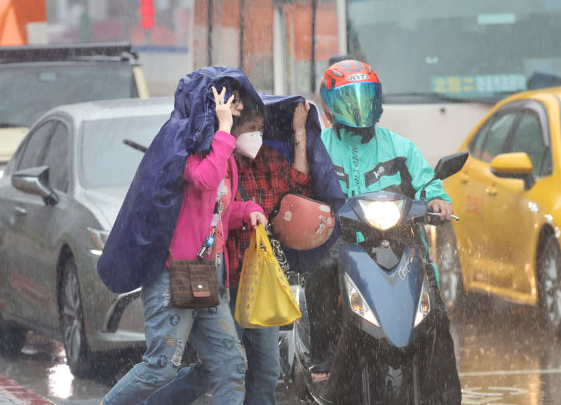 鋒面影響　台北下大雨 受鋒面影響，台北市區26日中午一度下起大雨，信義 區街頭有民眾沒帶雨傘，先以雨衣遮擋頭部，快速通 過馬路。 中央社記者王飛華攝  113年4月26日 