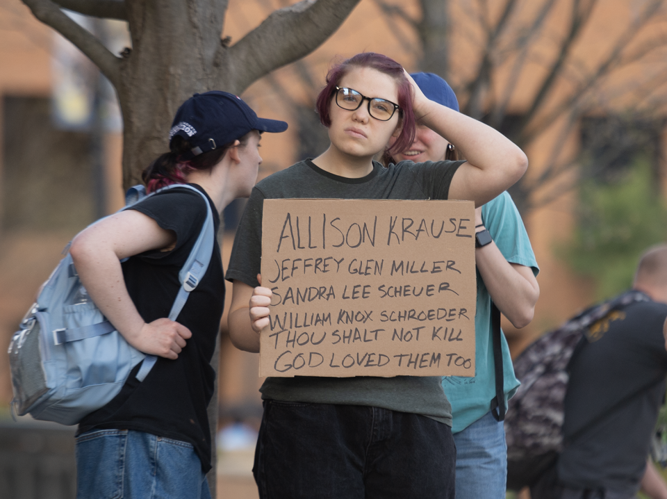 A demonstrator protesting an appearance by Kyle Rittenhouse at Kent State University on April 16, 2024. The sign lists names of four students killed during an anti-Vietnam War protest at the university on May 4, 1970.