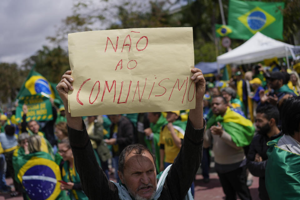 A supporter of Brazilian President Jair Bolsonaro holds a sign that reads in Portuguese: "No to Communism!" during a protest against his defeat in the country's presidential runoff, outside a military base in Sao Paulo, Brazil, Thursday, Nov. 3, 2022. Some supporters are calling on the military to keep Bolsonaro in power, even as his administration signaled a willingness to hand over the reins to his rival, President-elect Luiz Inacio Lula da Silva. (AP Photo/Matias Delacroix)