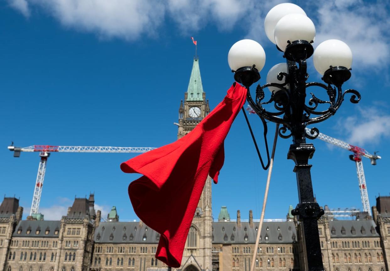 A red dress hangs on a light fixture to mark the National Day of Awareness for Missing and Murdered Indigenous Women, also known as Red Dress Day, in Ottawa on May 5, 2023. (Spencer Colby/The Canadian Press - image credit)