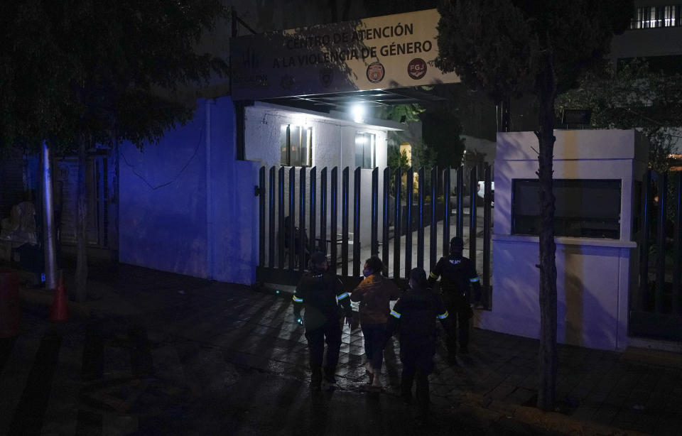 A woman is accompanied by police to file a complaint at a station that attends to gender violence cases in Naucalpan, State of Mexico, Mexico, Saturday, July 2, 2022. The sign above reads in Spanish "Gender Violence Attention Center." (AP Photo/Eduardo Verdugo)