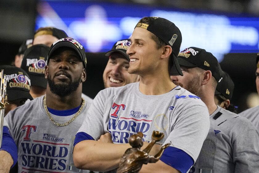 Texas Rangers shortstop Corey Seager stands next to the World Series trophy after his team defeated the Diamondbacks
